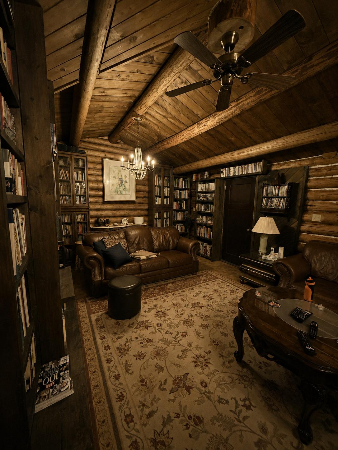The log-walled library lounge, lit by a small chandelier, with leather sofas and floor-to-ceiling bookshelves.