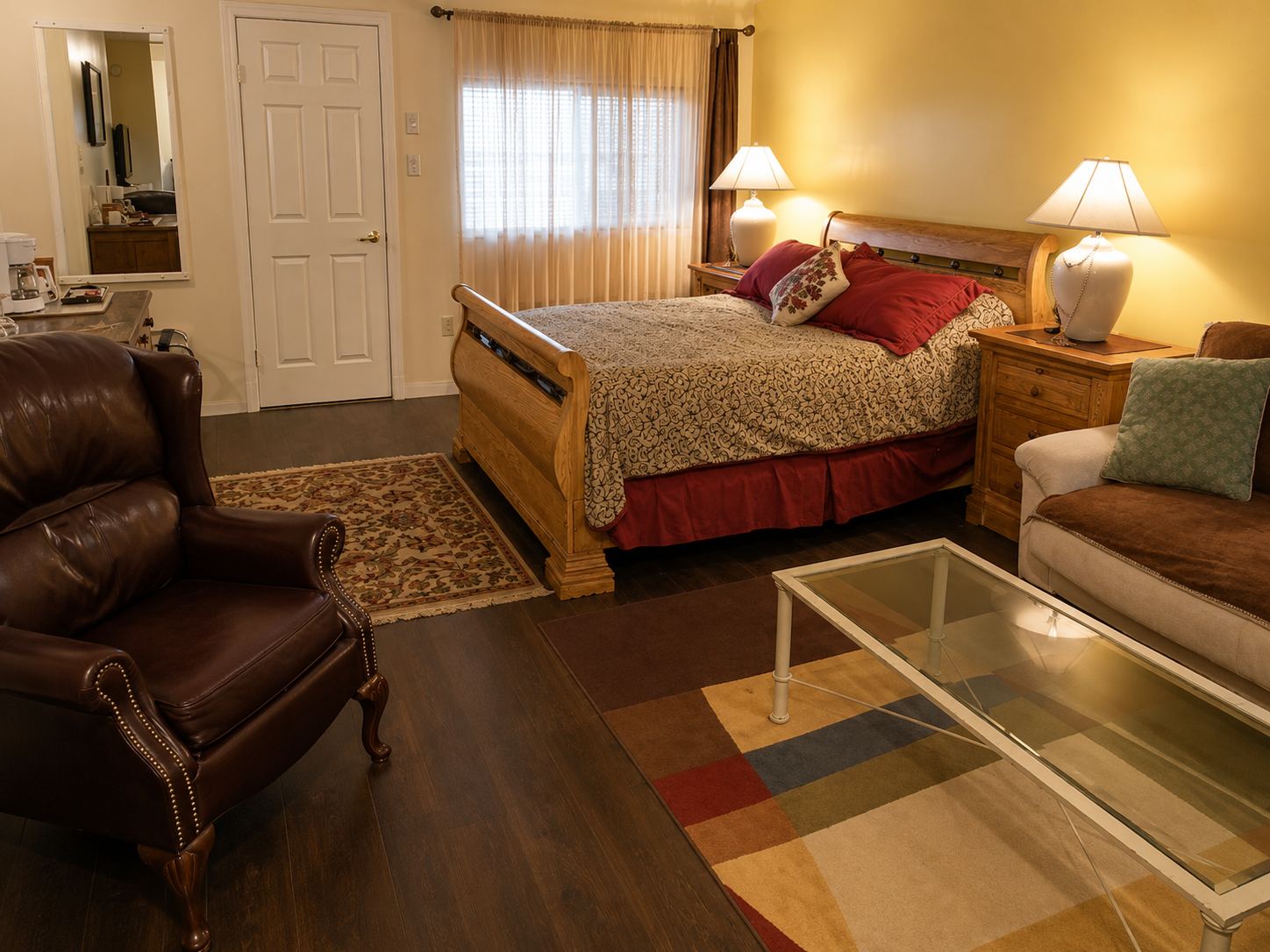 The Tucson suite: a queen bed in a wooden sleigh frame with lamps either side, a leather armchair and a sofa in the foreground.